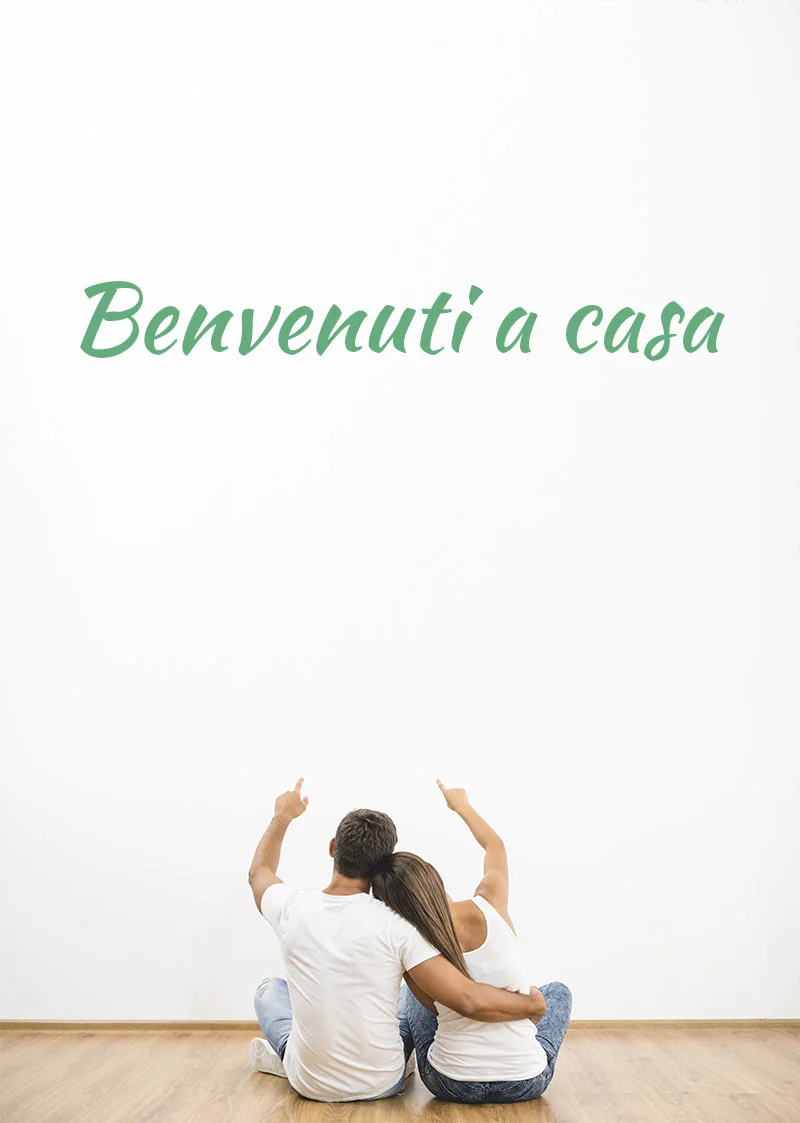 Benvenuti a casa — una coppia seduta guarda il claim scritto sulla parete di casa